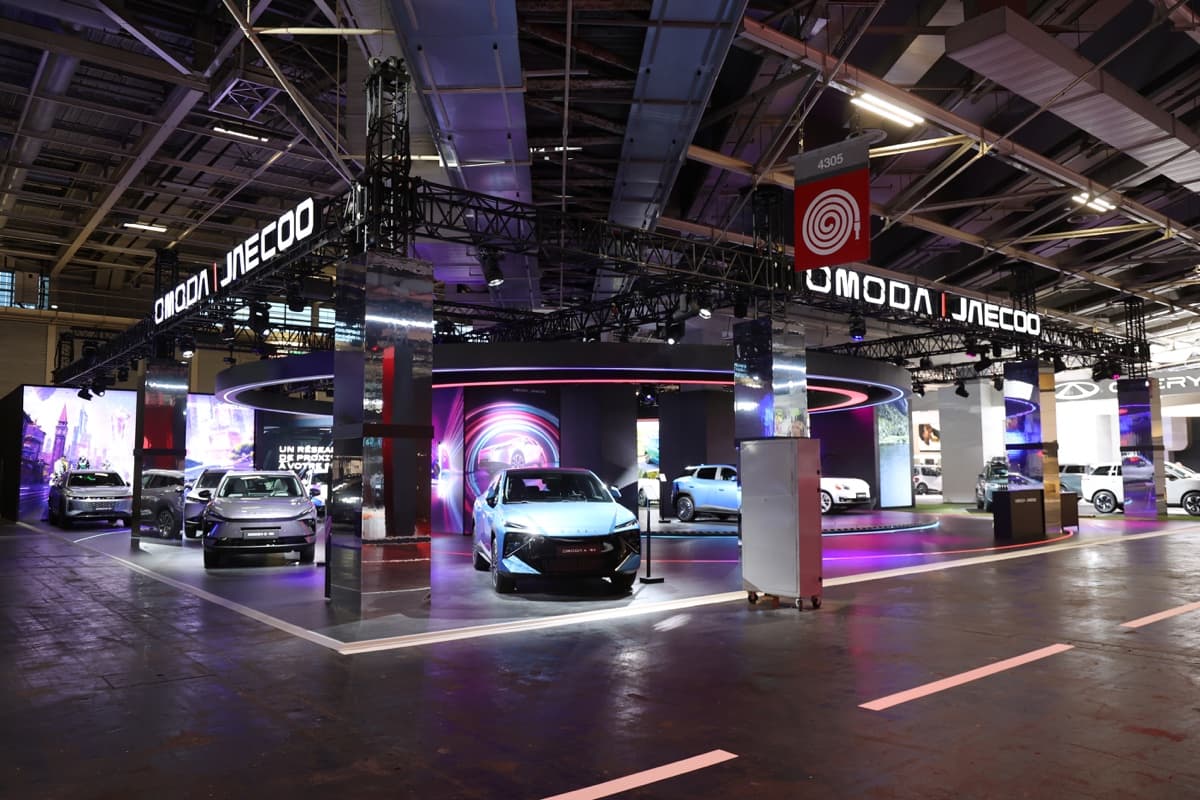 Stand Omoda & Jaecoo au Mondial de l'Auto 2026, structures noires, anneau lumineux aux néons et lettrages suspendus, conçu et réalisé par The Good Experience