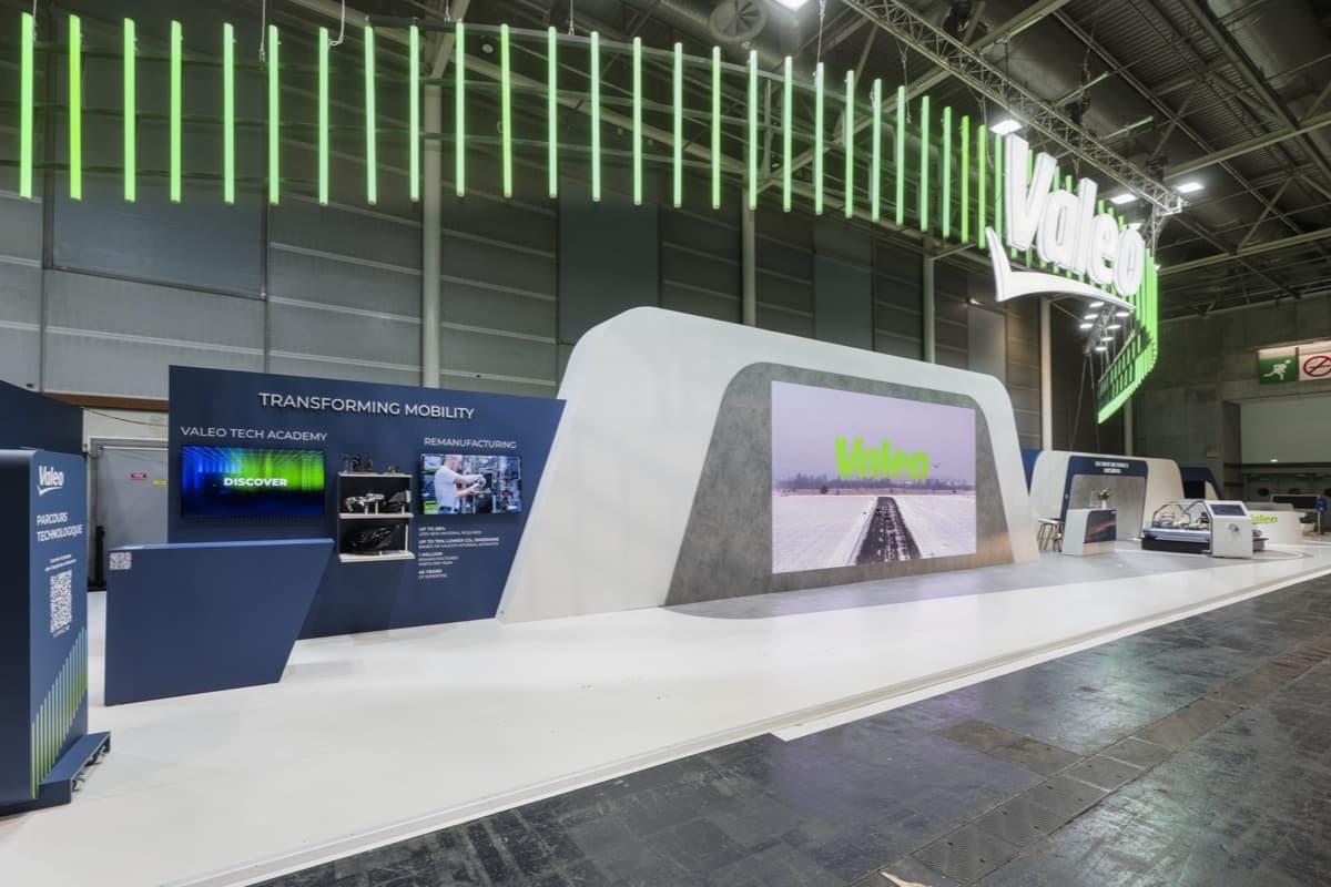 Stand Valeo au Mondial de l'Auto 2026, long linéaire blanc, grand écran et rampe lumineuse verte, conçu et réalisé par The Good Experience